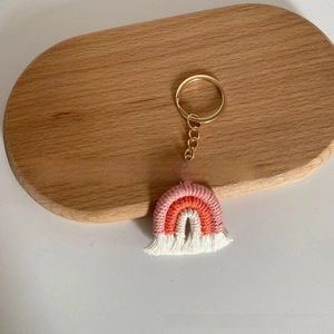 Close-up of handmade woven rainbow keychain with pastel cotton cords and golden ring
