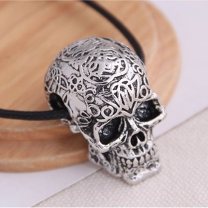 Vintage silver skull necklace with intricate carvings on a black cord for men