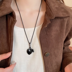 Close-up of heart-shaped obsidian stone pendant on a black woven cord necklace