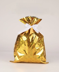 Close-up of golden Christmas gift bag with snowflake texture and white ribbon bow