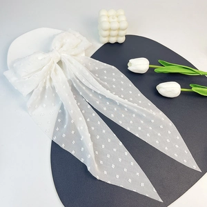 Detailed view of white Swiss dot chiffon bow clip with long ribbons and soft fabric texture
