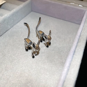 Detail view of silver cartoon donkey earrings with black enamel in a grey jewelry box