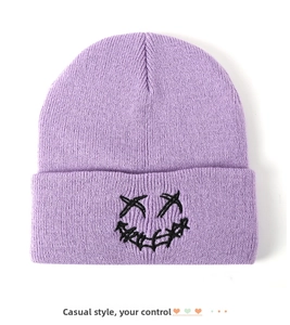 Close-up of lavender knit beanie featuring black embroidered prank smile face detail