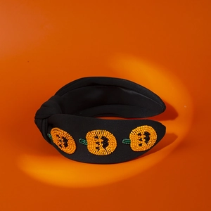 Detail of beaded pumpkin headband with handmade orange sequins on a wide black fabric band