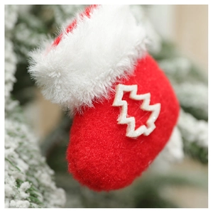 Detail of red plush Christmas sock ornament with white tree cutout on a festive tree