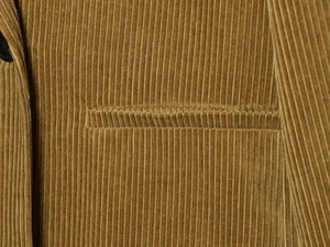 Close-up of ginger yellow corduroy fabric texture and pocket detail on fashion blazer