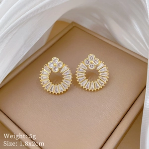 Macro shot of gold circular earrings with sparkling zircon on a champagne silk background