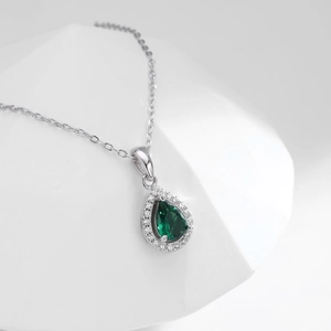 Detailed macro view of a green teardrop gemstone pendant surrounded by white crystals