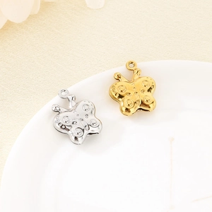 Detailed view of 3D hollow butterfly pendants in gold and silver steel on ceramic plate