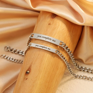 Detailed macro view of silver Cuban link couple bracelets with You Complete Me engraving
