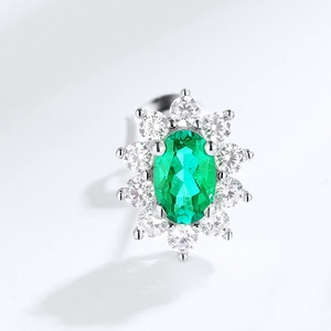 Detailed close-up of oval green emerald stud earrings with a sparkling halo setting