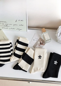 Flat lay of striped mid-calf cotton socks and star embroidery in black and white tones