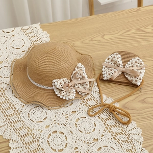 Détail d'un chapeau de paille et d'un sac assorti avec nœuds floraux et dentelle