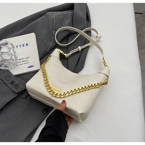 Close-up of white quilted bucket bag with gold chain strap on grey blazer fabric