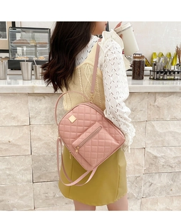 Pink quilted mini backpack with adjustable strap shown in a lifestyle cafe setting