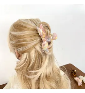 Détail de la pince à cheveux nœud en acétate marbré rose sur cheveux ondulés