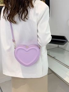 Vista posteriore di una modella con borsa a tracolla a forma di cuore color lavanda e blazer