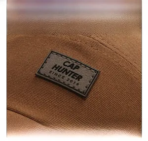 Dettaglio ravvicinato di un cappello da baseball in tela marrone con patch in pelle