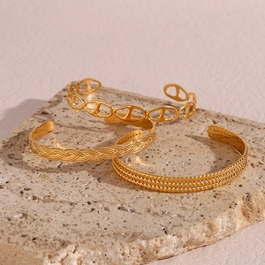 Detailed view of three gold adjustable cuff bracelets with woven and twisted patterns