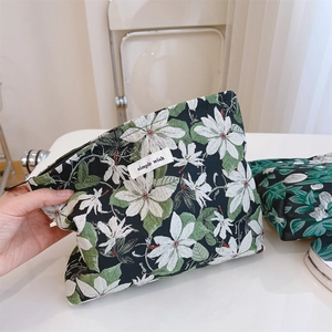 Close-up of black jacquard makeup bag with green floral pattern and Simple Wish label
