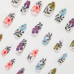 Floral press-on nails featuring hand-painted designs on almond shaped tips set on white