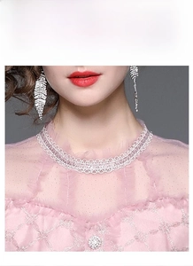 Détail de la robe rose brodée avec col en dentelle et boutons en strass brillants
