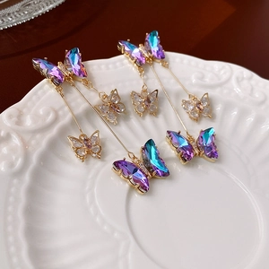 Macro shot of iridescent crystal butterfly tassels on an elegant gold chain earring