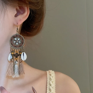 Macro detail of Bohemian long tassel earrings with wood beads and natural shell accents