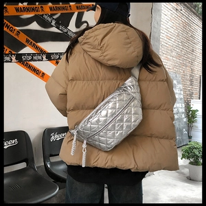 Detailed view of silver quilted waist bag with woven zipper pull and adjustable strap