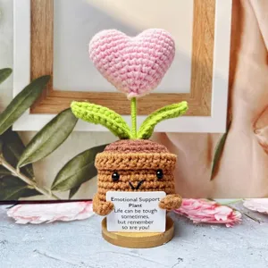 Close-up of handmade crochet heart plant with green leaves and inspirational card