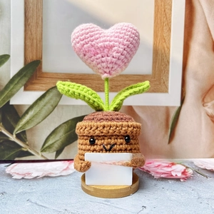 Close-up of handmade crochet heart plant with green leaves and inspirational card