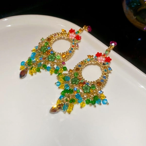Detailed macro view of colorful crystal flower tassel earrings on white porcelain