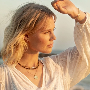 Bohemian gold layered necklace with tiger eye beads and round pendant on a female model