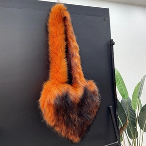 Detail of heart-shaped faux fur bag featuring orange and brown long plush texture