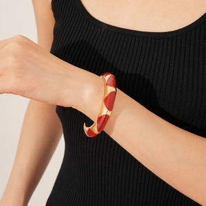 Detail of French vintage enamel open cuff bracelet in red and gold on a female wrist