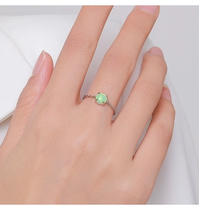 Macro shot of 925 sterling silver chain ring with a round green opal on a finger