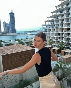Détail d'un haut noir sans manches chic avec un pantalon en satin beige en décor urbain