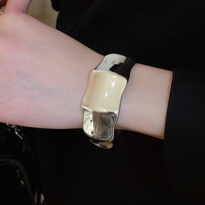 Macro view of wide irregular silver bangle with high-polish mirror finish on a model