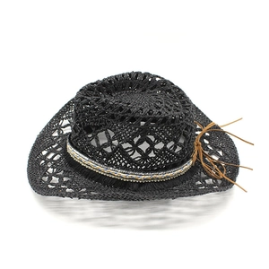 Détail d'un chapeau de cow-boy en paille noire avec motifs ajourés et ruban de perles