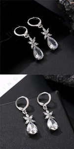 Detailed view of silver flower earrings with water drop zircon on a black jewelry box