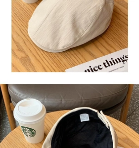 Detail view of beige cotton blend baker boy cap with inner label and fabric texture