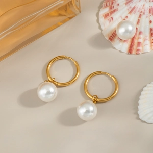 Primer plano de elegantes aros de acero inoxidable de 18K con colgantes de perlas