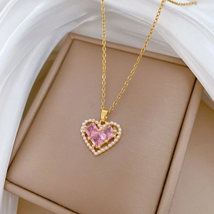 Detail of gold heart pendant with pink gemstone and white pearl on silk background