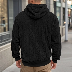 Close-up of men's black knit hoodie showing thick cable texture and ribbed cuffs detail