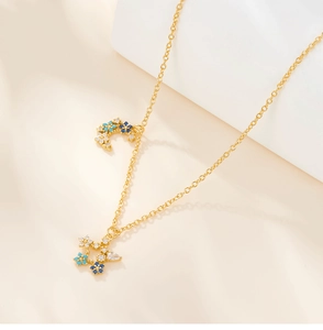 Detailed view of golden star and moon pendant with blue and clear zircon stones on a chain