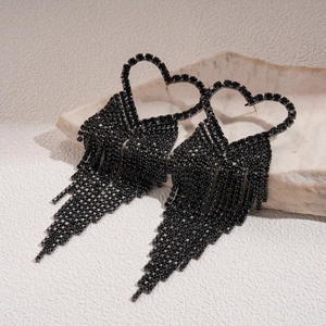 Gothic black heart rhinestone tassel drop earrings displayed on a natural stone base