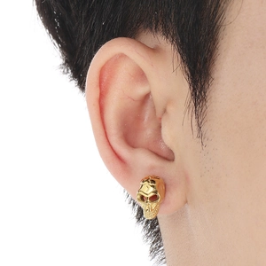 Close-up of a gold-colored skull stud earring on ear in a punk gothic style