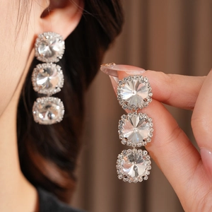 Detailed close-up of triple-layered round crystal earrings with shimmering silver finish