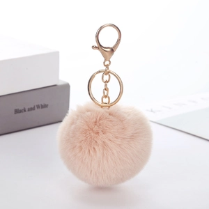 Close-up of a soft pink faux rabbit fur pom pom keychain with gold metal lobster clasp