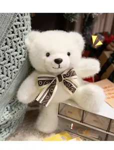 Close-up of a creamy white plush teddy bear featuring a brown patterned bow tie